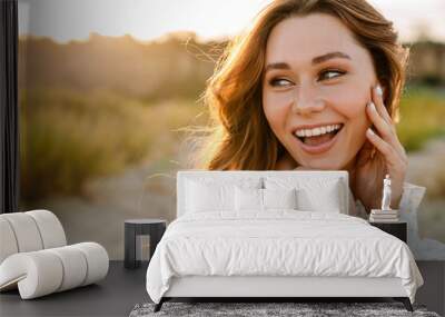 Young caucasian brunette woman smiling and looking aside outdoors Wall mural