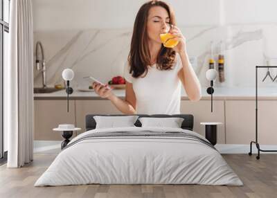 Young joyful woman drinking orange juice Wall mural