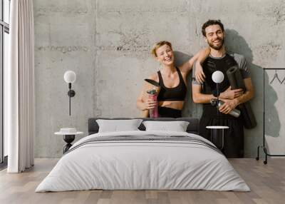 Young man and woman smiling while working out together on parking Wall mural