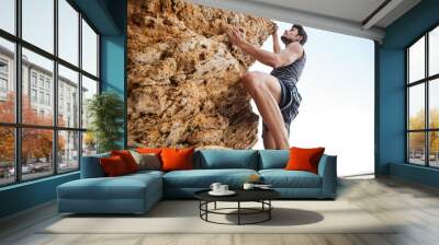 Young man climbing natural rocky wall Wall mural