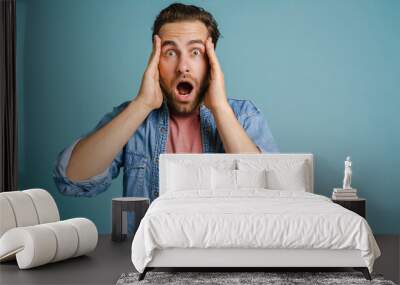 Young man holding his head while expressing surprise Wall mural