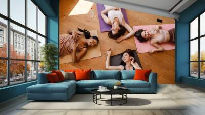 Young multiracial women laughing together during yoga class Wall mural