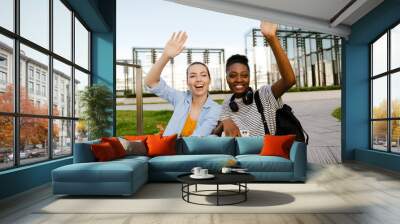 Young multiracial women smiling and waving hands at city street Wall mural