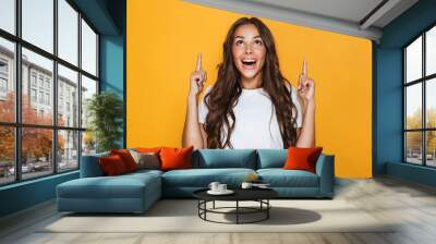 Young pretty woman posing isolated over yellow background showing copyspace. Wall mural