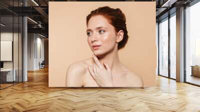 Young redhead woman posing isolated over beige wall background. Wall mural