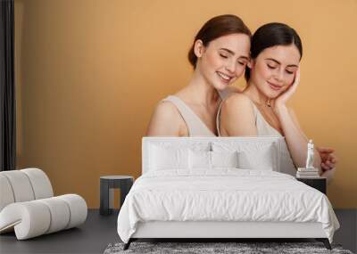 Young two women in undershirt hugging and smiling at camera Wall mural