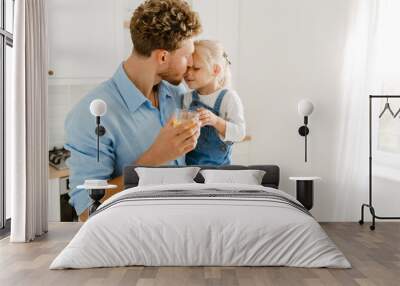 Young white father holding his daughter while drinking tea together Wall mural