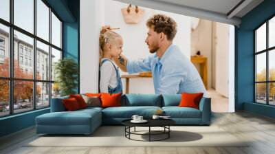 Young white father measuring height of his little daughter at home Wall mural