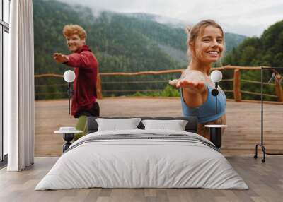 Young white man and woman practicing yoga on fitness mats in forest Wall mural