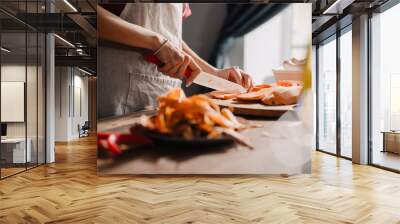 Young woman cutting sweet potato while cooking in kitchen Wall mural