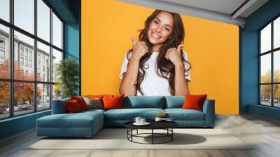 Young woman isolated over yellow background showing thumbs up gesture. Wall mural