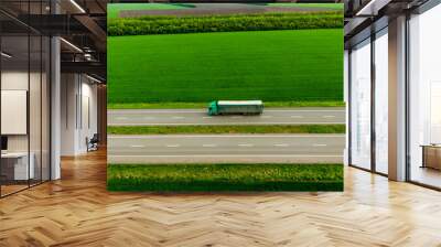 green truck driving on asphalt road along the green fields. seen from the air. Aerial view landscape. drone photography.  cargo delivery Wall mural