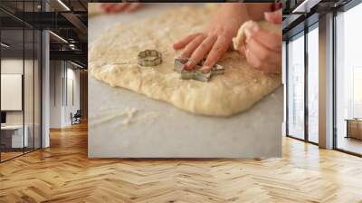 Close up of child playing with dough while preparing traditional Christmas cookies with cutters Wall mural