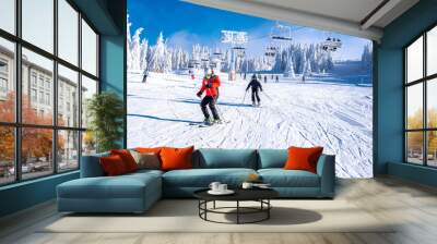 People enjoying skiing and snowboarding in mountain ski resort with beautiful winter landscape in the background Wall mural