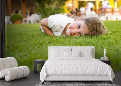 Smiling girl laying in the grass on a summer day and having fun Wall mural