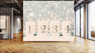 Advent candles 1, 2,3,4 in front of concrete background in the snow with colorful lights and gray trees Wall mural