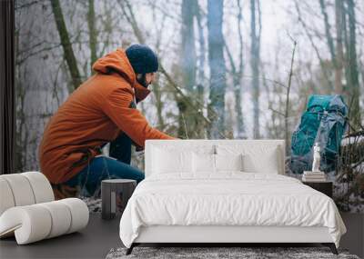 a tourist is making camp fire in the winter woods Wall mural