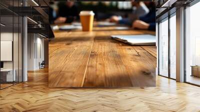 A close-up of a wooden table in a meeting room, featuring notebooks and a coffee cup, creating a collaborative atmosphere. Wall mural