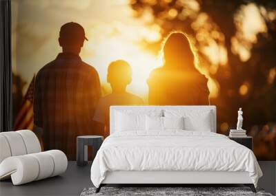 A silhouette of a family—two adults and a child—standing together at sunset, with warm golden light illuminating the scene. Wall mural