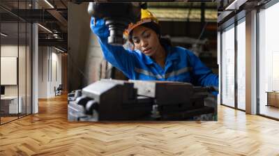 African black woman wearing blue safety uniform working control with heavy machine in factory Wall mural