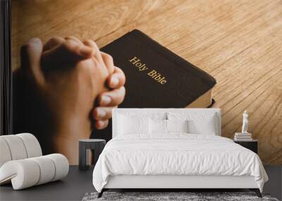 Women praying, Hands clasped together on her Bible in the whiteness over wooden table. Wall mural