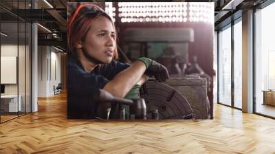 Exhausted Asian female engineer taking break on industrial machine - Diverse factory employee woman suffering depression worry and anxiety at work - Overtime, regulations and immigrant worker concept Wall mural