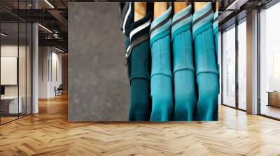 Five green hanging cotton polo shirts - Side view of one dark and four light green teal unisex shirts with collar on wooden hangars Wall mural