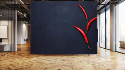 Three red chili peppers on the dark blue stone background. Wall mural