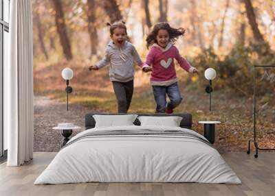 two cute little girls run through the park during the autumn sunny afternoon. Two small disobedient girls have running and having fun outside. two little happy girls. Wall mural