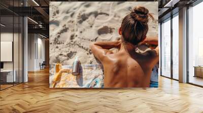 Woman sunbathing on the sand on the beach on her vacation trip, lying face down with her back tanning, enjoying a relaxing summer trip by the sea Wall mural