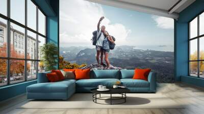 Couple of hikers taking selfie from top of the mountain with valley view on the background Wall mural