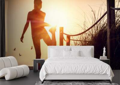 Woman performs stretching exercises on a beach at sunrise Wall mural