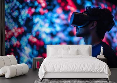 A young man wearing a VR headset looks at a screen with an abstract pattern of red and blue lights. Wall mural