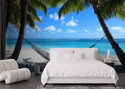 Hammock strung between two palm trees on a white sand beach with a turquoise ocean behind. Wall mural