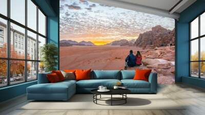 A young couple is watching at sunrise over wadi rum desert in Jordan Wall mural