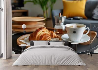 Cozy breakfast scene with croissant and coffee on wooden plate beside open book on round table in inviting home interior Wall mural