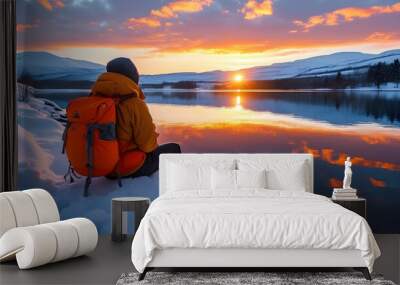 Tranquil winter sunset by the snowy lakeside with a person and an orange backpack Wall mural