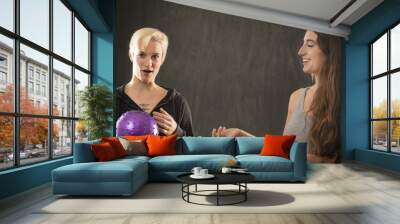 Two young women playing with purple ball in the studio. Wall mural