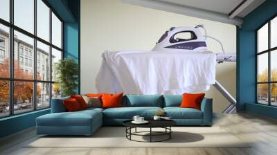 Clothes iron on ironing board with garments inside house Wall mural