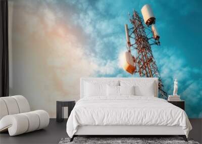 A tall telecommunication tower stands majestically against a partly cloudy sky, illuminated by warm sunlight, symbolizing connectivity and modern technology. Wall mural