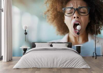 A woman with glasses yawning while holding and reading a document, showing signs of fatigue or boredom. Emphasizes the monotony or tediousness of the task at hand. Wall mural