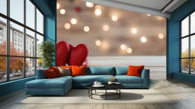 Two red hearts are on a wooden table. The table is surrounded by a blurry background. Concept of warmth and love, as the two hearts are placed close together Wall mural