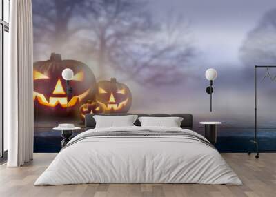 A ghostly dusk in the countryside with spooky Jack O' Lanterns in the fog with bare trees in the background. Wall mural