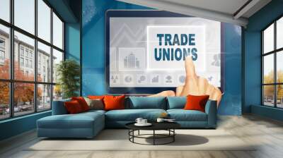 A hand selecting a Trade Unions business concept on a computer tablet screen with a colorful background. Wall mural