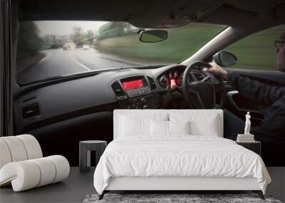 A man driving a car at speed in wet weather conditions. Wall mural