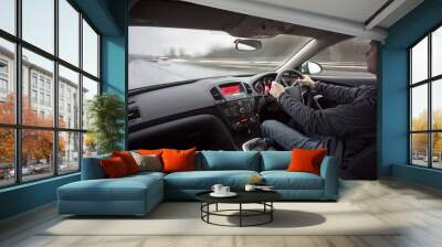 A man driving a car at speed in wet weather conditions. Wall mural