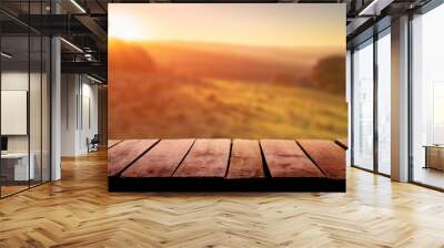 A wooden table top planks product display with a blurred background scene of farmland at sunset. Wall mural