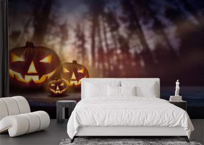 Spooky Jack O' Lanterns at sunset, dusk in pine forest towering up in the background at night. Wall mural