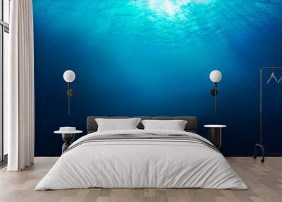 Sunlight shining through the surface of the blue ocean, sea, with dark waters below. Wall mural