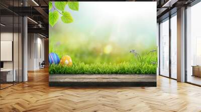 Three painted easter eggs celebrating a Happy Easter on a spring day with a green grass meadow, bright sunlight, tree leaves and a background with copy space and a wooden bench to display products. Wall mural